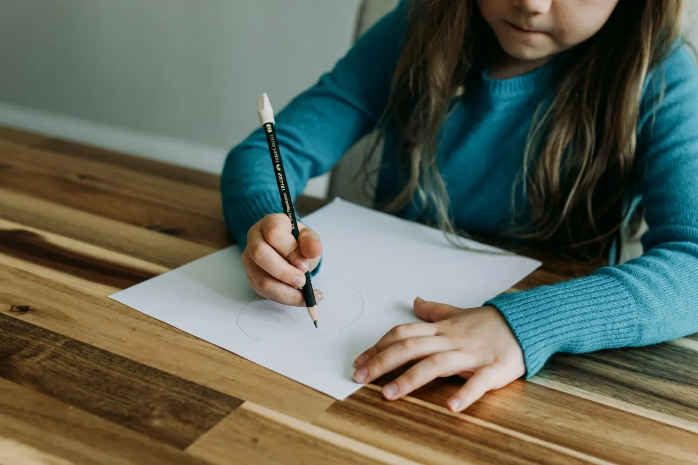 A child writing on paper with a pencil